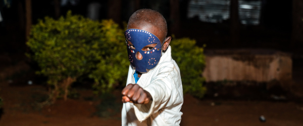 Kevin, onherkenbaar in beeld gebracht door een blauw masker, doet een taekwando beweging