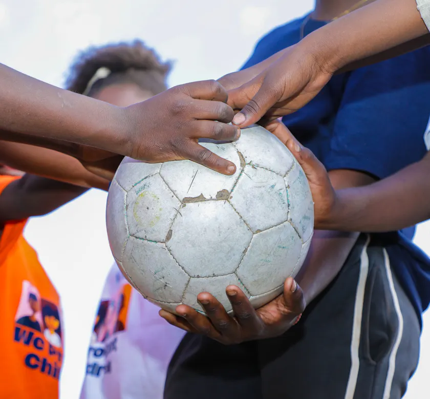 Kinderen houden een voetbal vast.